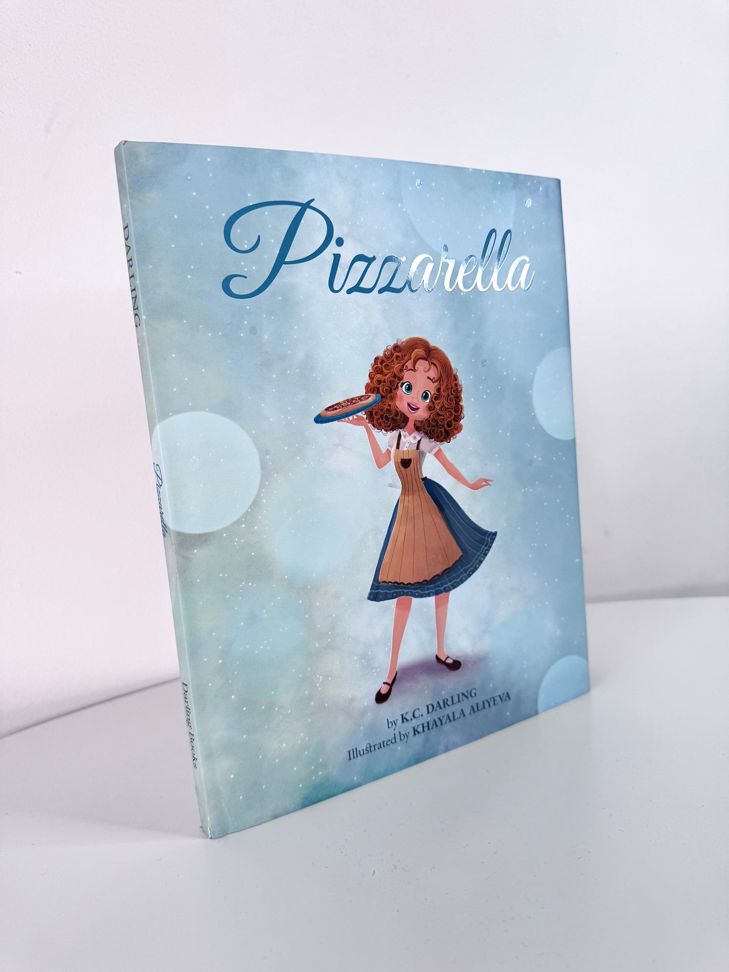 Book titled 'Pizzarella' with an illustration of a character on the cover against a light blue background.